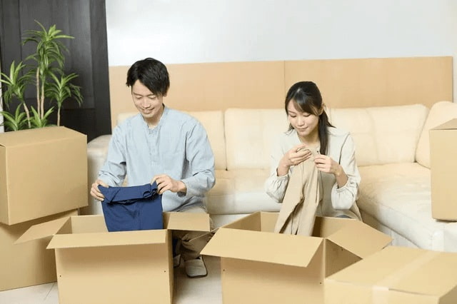 服を箱に詰めている夫婦