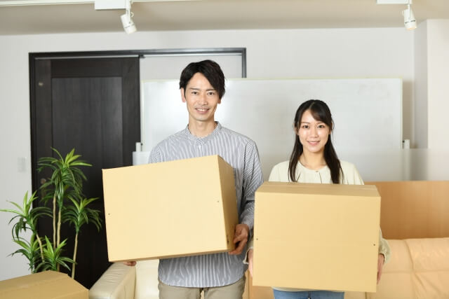 部屋でダンボールを持ってる男女