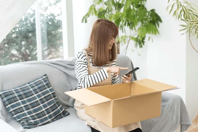 ソファに座ってダンボールを持っている女性