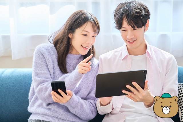 スマホとタブレットの画面を見比べる男女