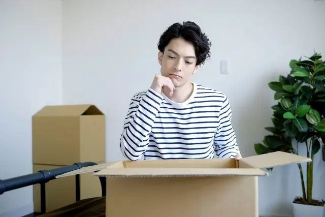 引越しのダンボールを前に考える男性
