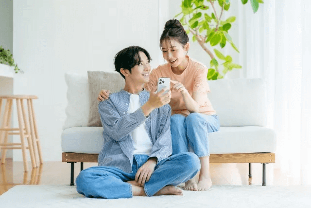 リビングでスマホを見る若いカップル