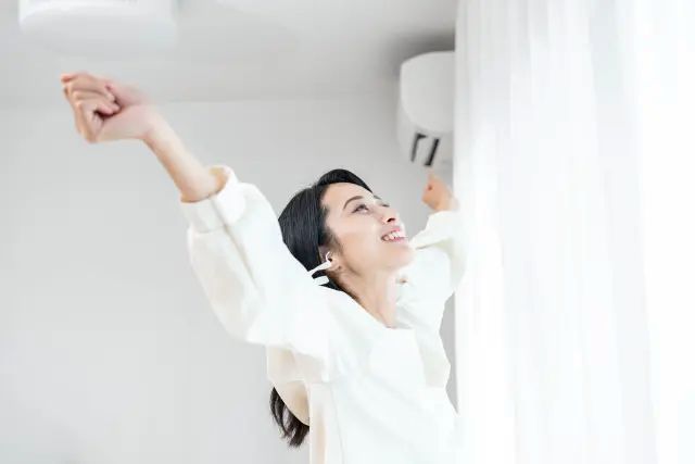 リビングの窓のそばで伸びをする女性