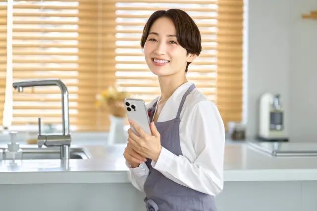 キッチンでスマホを持つ主婦