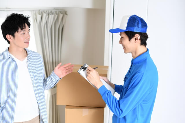 部屋で会話をする男性作業員と若い男性客.