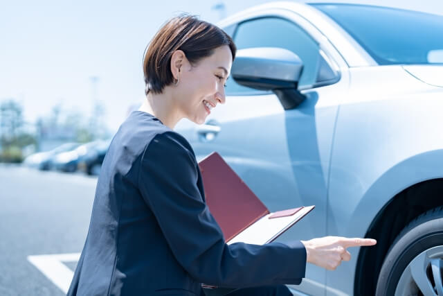 車の傷や凹みを確認する女性