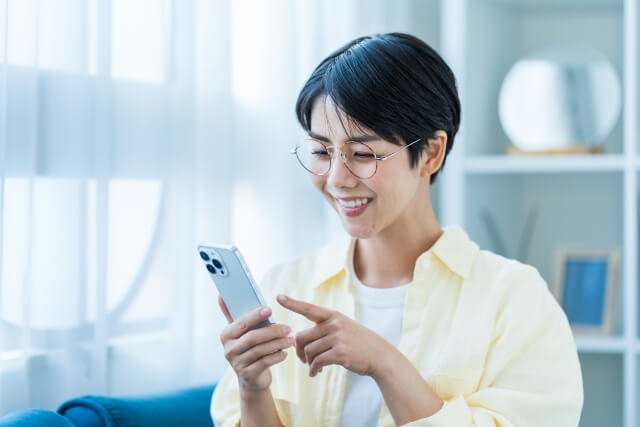 リビングでスマホを操作する若い女性