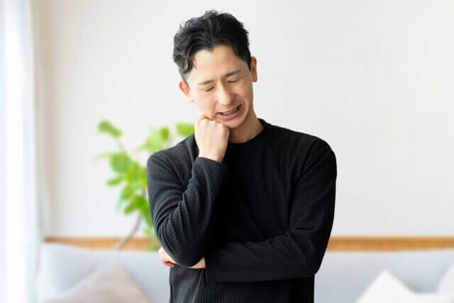 リビングで考えごとをする男性